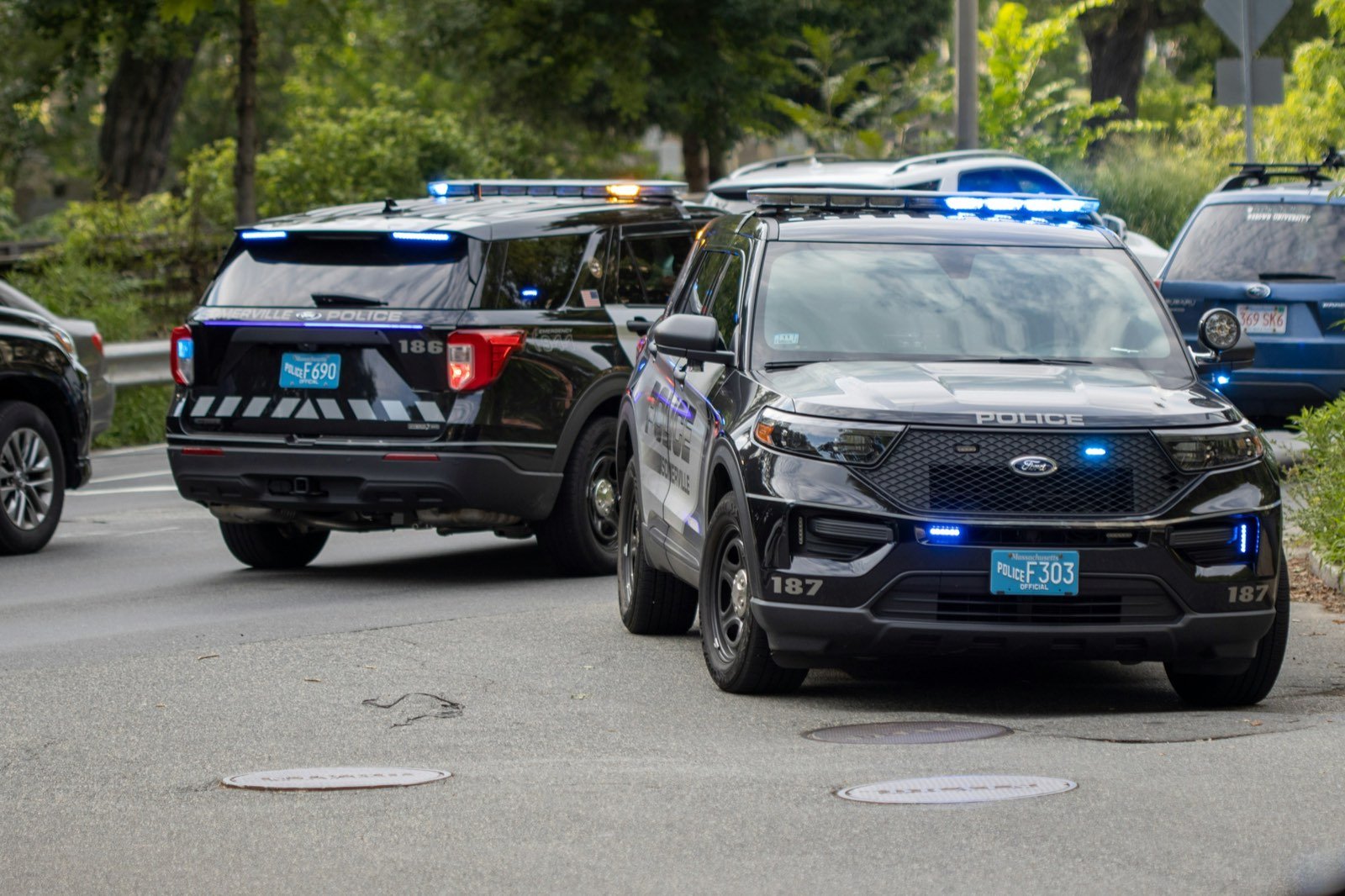Two marked police SUVs with emergency lights on
